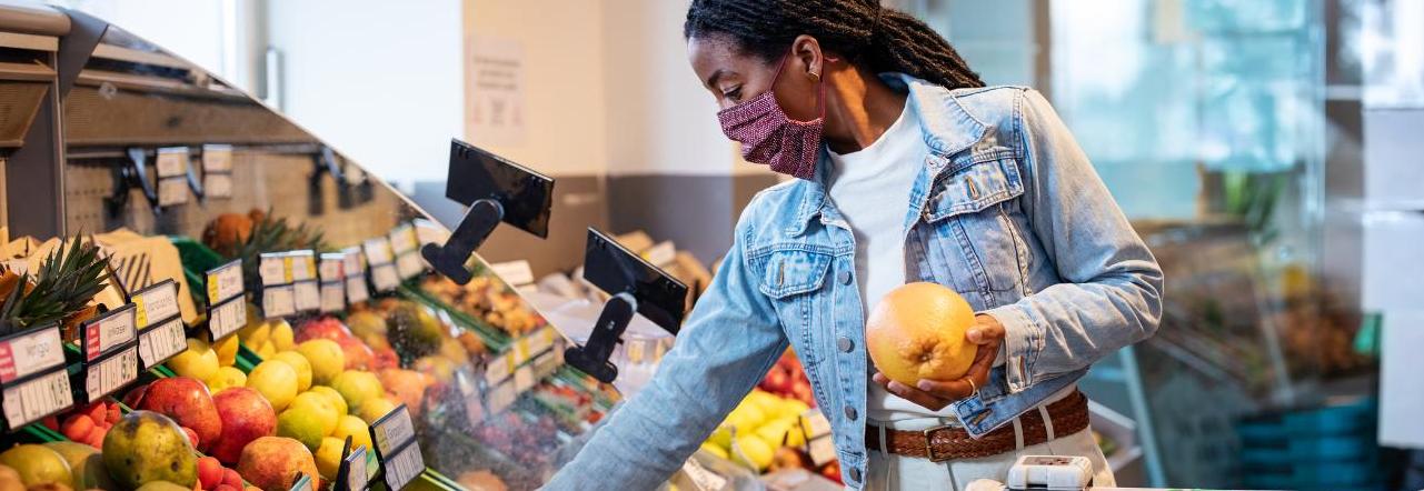 Mulher negra escolhe frutas no mercado visando evitar desperdício