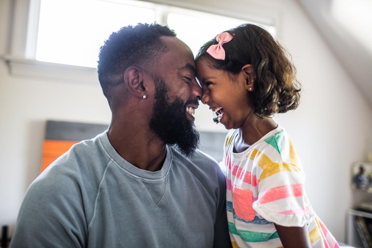 Pai e filha  negros se abraçando felizes
