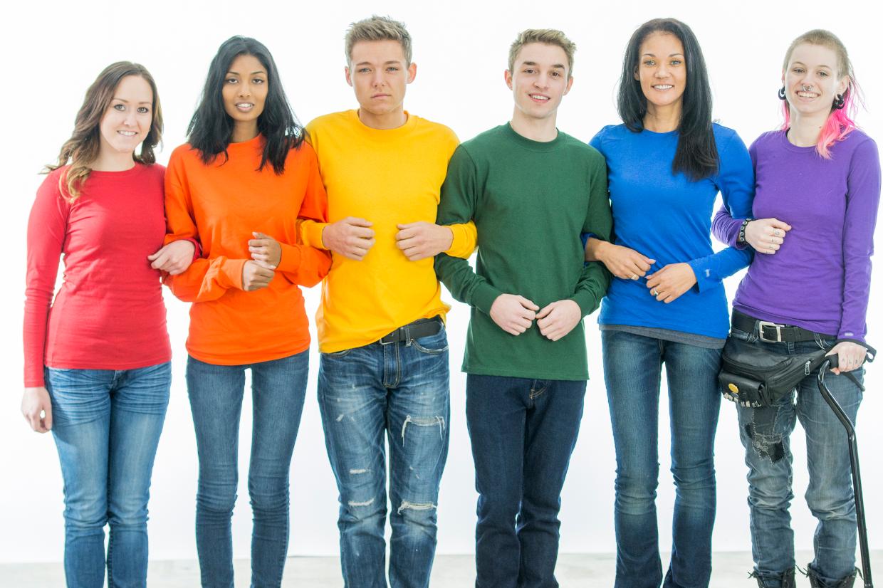 grupo de jovens enfileirados e abraçados com cores de blusas do movimento LGBTI+