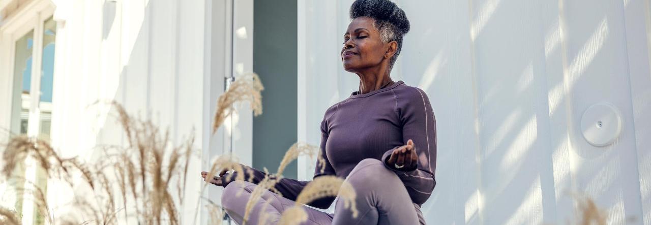 mulher negra faz ioga do lado de fora de sua casa