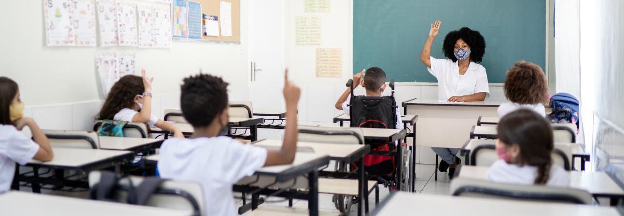 Crianças com máscara e em distanciamento social, assistem aula na escola